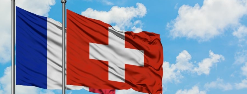 Drapeau suisse flottant sous un ciel ensoleillé, symbole de stabilité pour les investissements transfrontaliers France-Suisse.