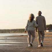 Un couple senior se promène sur la plage, symbolisant la sérénité et la planification successorale sereine.